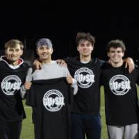 Students holding up and wearing championship shirts from a ultimate frisbee tournament